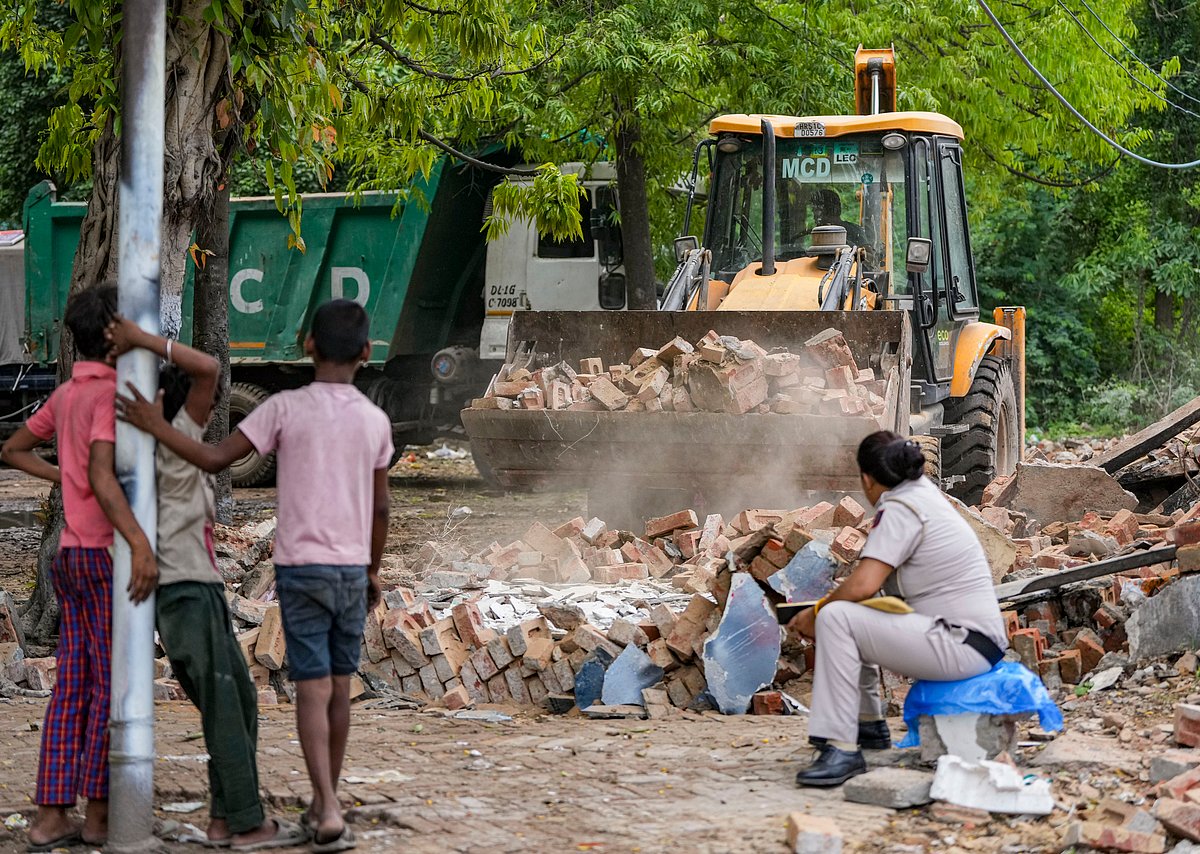 via  PTI : Children watch as bulldozer clears rubble during a demolition drive in Delhi. 
Credits