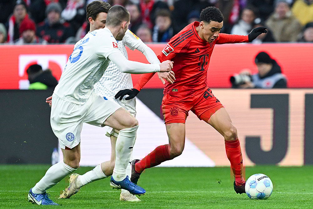 | Photo: Sven Hoppe/dpa via AP : Bundesliga 2024-25: Bayern's Jamal Musiala challenges for the ball with Kiel's Magnus Knudsen and David Zec