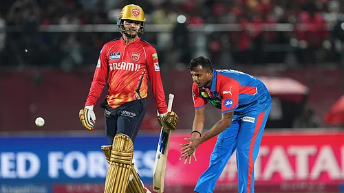 AP Photo/Ashwini Bhatia : Delhi Capitals T Natarajan, right, collects the ball as Punjab Kings Priyansh Arya walks past during the Indian Premier League cricket match in Dharamshala.