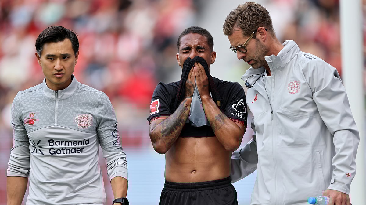 Arthur is walked off the pitch by Bayer Leverkusen's medical staff.