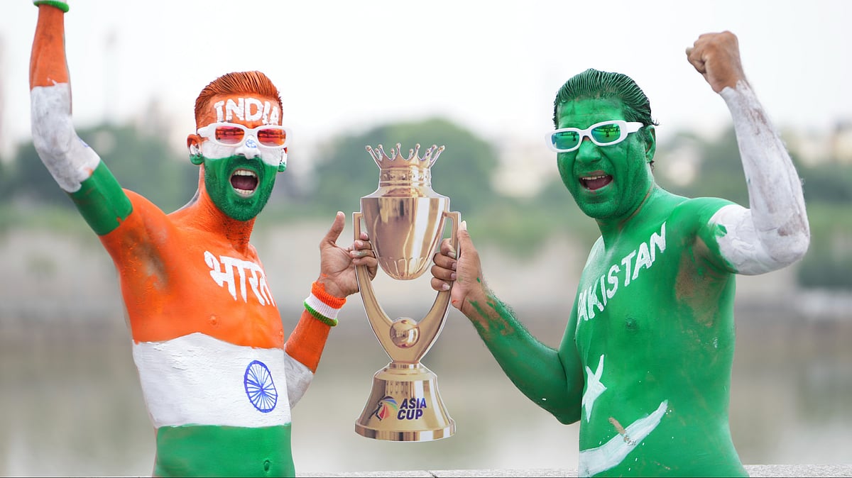 | Photo: AP/Ajit Solanki : Two Indian cricket fans, with their bodies painted in the colors of Indian and Pakistan flags, pose for the media with a cutout image of the Asia Cup trophy in Ahmedabad, India on the eve of the Asia Cup match between the two countries, Saturday, Sept. 13, 2025.