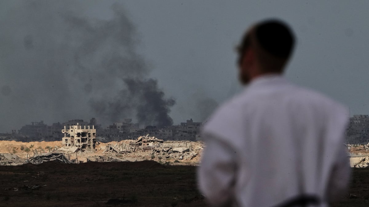 (AP Photo/Ariel Schalit) : A Jewish man observes smoke rising to the sky after an explosion in the Gaza Strip, as seen from southern Israel, Thursday, Oct. 9, 2025, following the announcement that Israel and Hamas have agreed to the first phase of a peace plan to pause the fighting. 