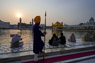 | Photo: PTI/Shiva Sharma : People sit near Amrit Sarovar at the Golden Temple on the occasion of Guru Nanak Jayanti, in Amritsar.
