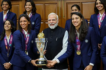 | Photo: Handout via PTI : Prime Minister Narendra Modi holding the ICC Womens Cricket World Cup winners trophy as he poses for a photograph with the winning Indian women cricket team in New Delhi.