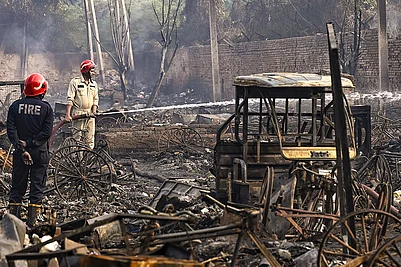 | Photo: PTI : New Delhi: Firemen spray water on charred remains after a fire broke out spreading to around 500 shanties near Rithala metro station, at Rohini area, in New Delhi. Police said several LPG cylinders were said to have exploded late Friday evening, intensifying the blaze and triggering panic among residents.