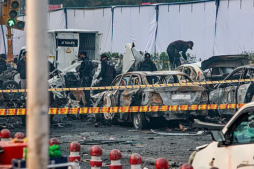 | Photo: PTI : Charred remains of vehicles at a cordoned off area following a blast that occurred near Red Fort Metro Station on 10 November.