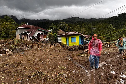 | Photo: AP/Ade Yuandha : People walk past damaged houses at a village affected by flood in Malalak, West Sumatra, Indonesia.