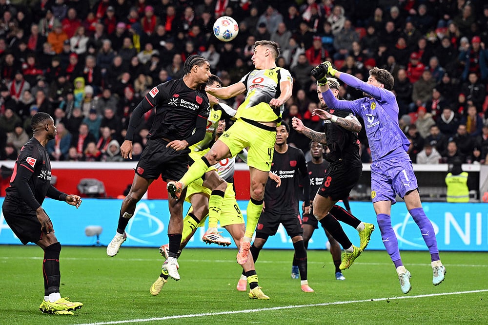 | Photo: Federico Gambarini/dpa via AP : Bayer's Loïc Badé, center left, and Borussia's Nico Schlotterbeck fight for the ball during the German Bundesliga soccer match between Bayer Leverkusen and Borussia Dortmund in Leverkusen, Germany.