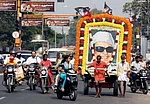 PTI Photo : Coimbatore: Two fans of MG Ramachandran (MGR), former Chief Minister of Tamilnadu, ferry his life-size poster through a street to mark his 25th death anniversary in Coimbatore on Monday.