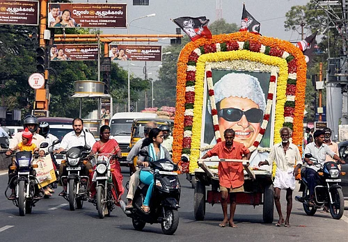 PTI Photo : Coimbatore: Two fans of MG Ramachandran (MGR), former Chief Minister of Tamilnadu, ferry his life-size poster through a street to mark his 25th death anniversary in Coimbatore on Monday.