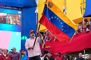 Ariana Cubillos : President Nicolas Maduro waves a Venezuelan flag during a swearing-in event for government-organized community committees at the presidential palace in Caracas, Venezuela, Monday, Dec. 1, 2025.