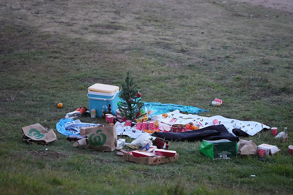 | Photo: AP/Mark Baker : A small Christmas tree is at the center of an abandoned holiday picnic at Bondi Beach after a reported shooting in Sydney.
