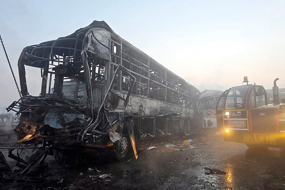 | Photo: PTI : Cranes clear the charred remains of buses after a fog-hit pile-up involving several buses and cars triggered fires on the Yamuna Expressway, in Mathura.