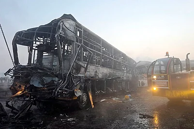 | Photo: PTI : Cranes clear the charred remains of buses after a fog-hit pile-up involving several buses and cars triggered fires on the Yamuna Expressway, in Mathura.