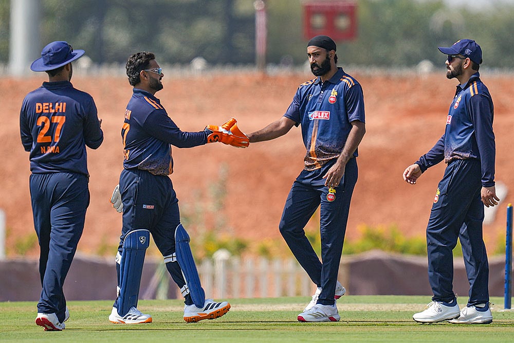 | Photo: PTI/Shailendra Bhojak : From left, Delhis Nitish Rana with captain Rishabh Pant and teammates Simarjeet Singh and Virat Kohli celebrates a dismissal during the Vijay Hazare Trophy 2025-26 cricket match between Andhra and Delhi, at BCCI Centre of Excellence Ground, in Bengaluru.