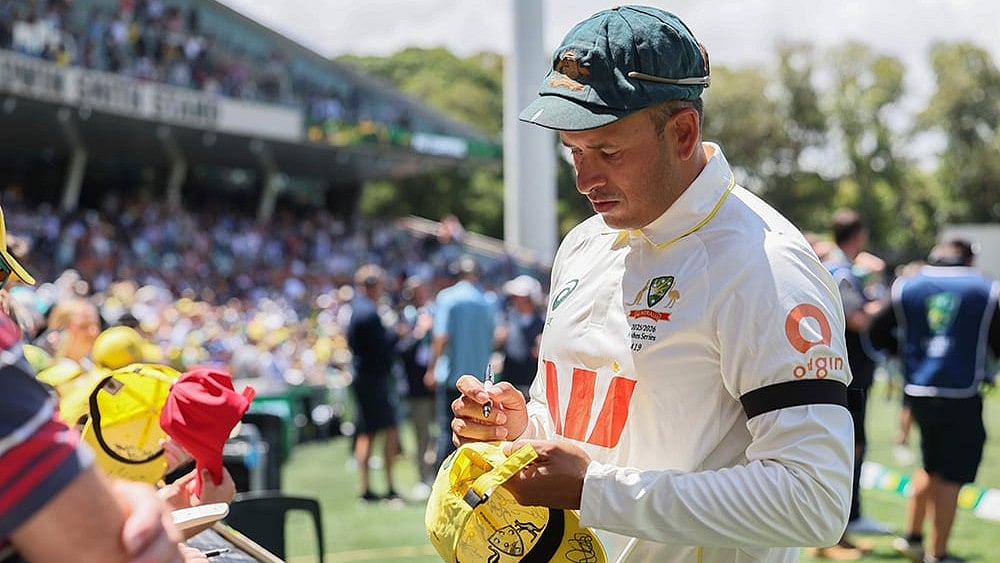 | Photo: AP/James Elsby : Australias Usman Khawaja sign autograph to fans after they won the third Ashes cricket test match against England in Adelaide, Australia.