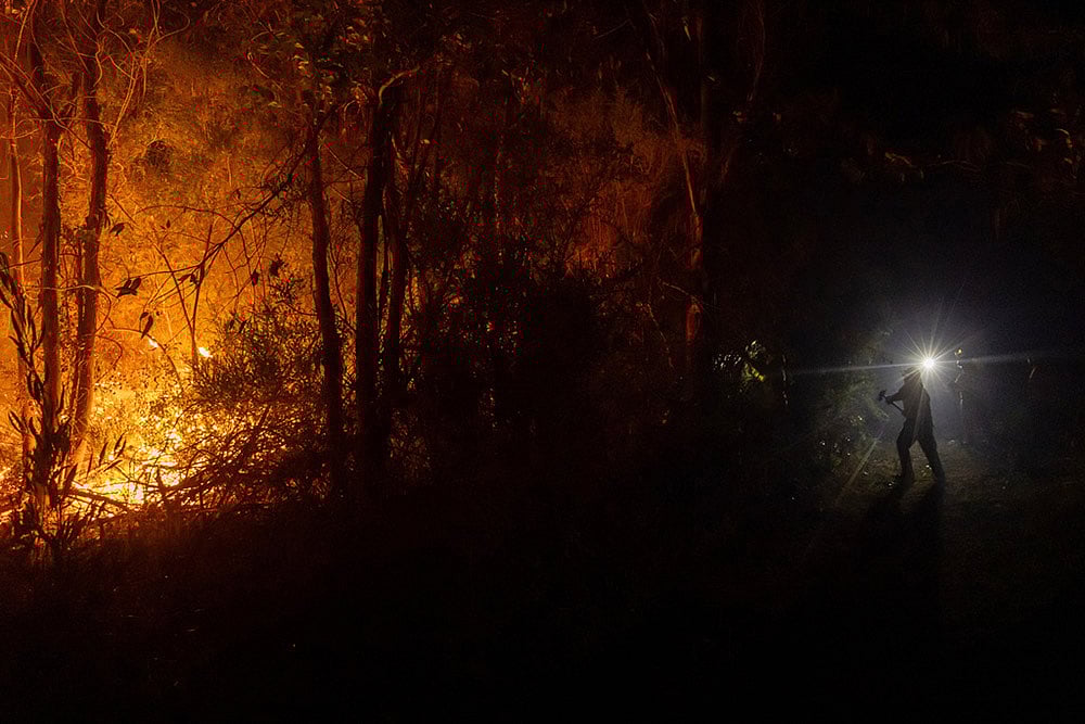 | Photo: AP/Javier Torres : Firefighters battle flames spreading through a forested area near Concepcion, Chile.