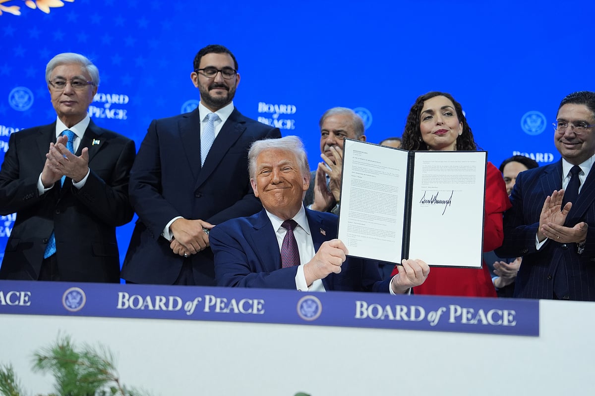 Evan Vucci : President Donald Trump, center, holds up a signed Board of Peace charter during the Annual Meeting of the World Economic Forum in Davos, Switzerland, Thursday, Jan. 22, 2026