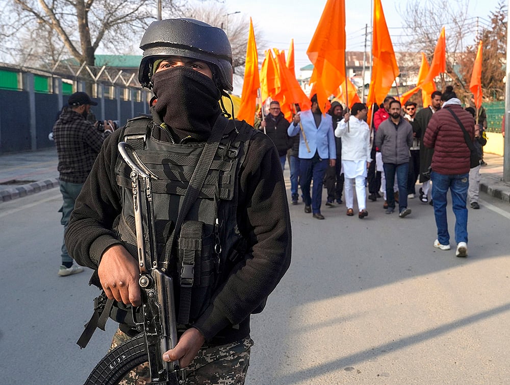 | Photo: PTI/S Irfan : A jawan keeps watch as people participate in a cross-country Dhwaj Yatra organised as part of celebrations of 100 years of Rashtriya Swayamsevak Sangh (RSS), in Srinagar. The rally commenced from historic Lal Chowk on Friday, and is scheduled to culminate in Kanyakumari. 