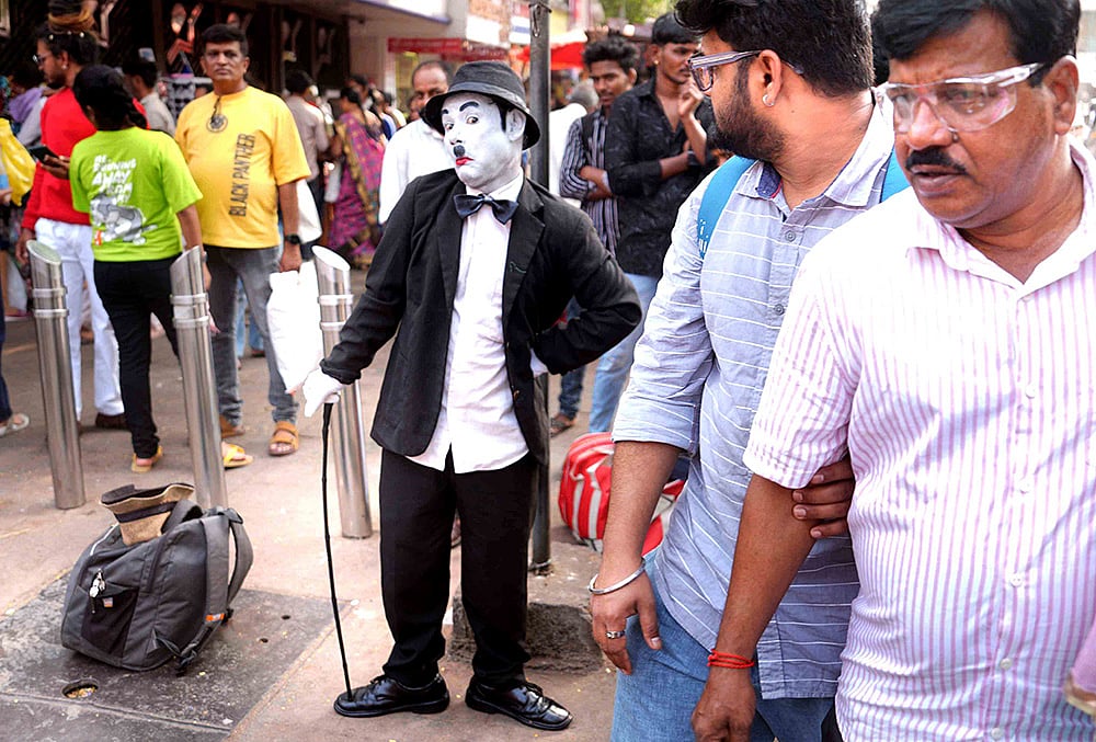 | Photo: Dinesh Parab/Outlook : Dressed as Charlie Chaplin, Afsar Khan greets a passerby with a warm handshake on the busy streets of Dadar, sharing a moment of joy.