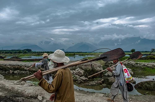 IMAGO / Middle East Images : Sand Mining in India Workers carry their tools to mine sand from the Asia s biggest sweet water lake Wular at dawn in Bandipora, India-administered Jammu and Kashmir, on Monday July 14, 2025.
