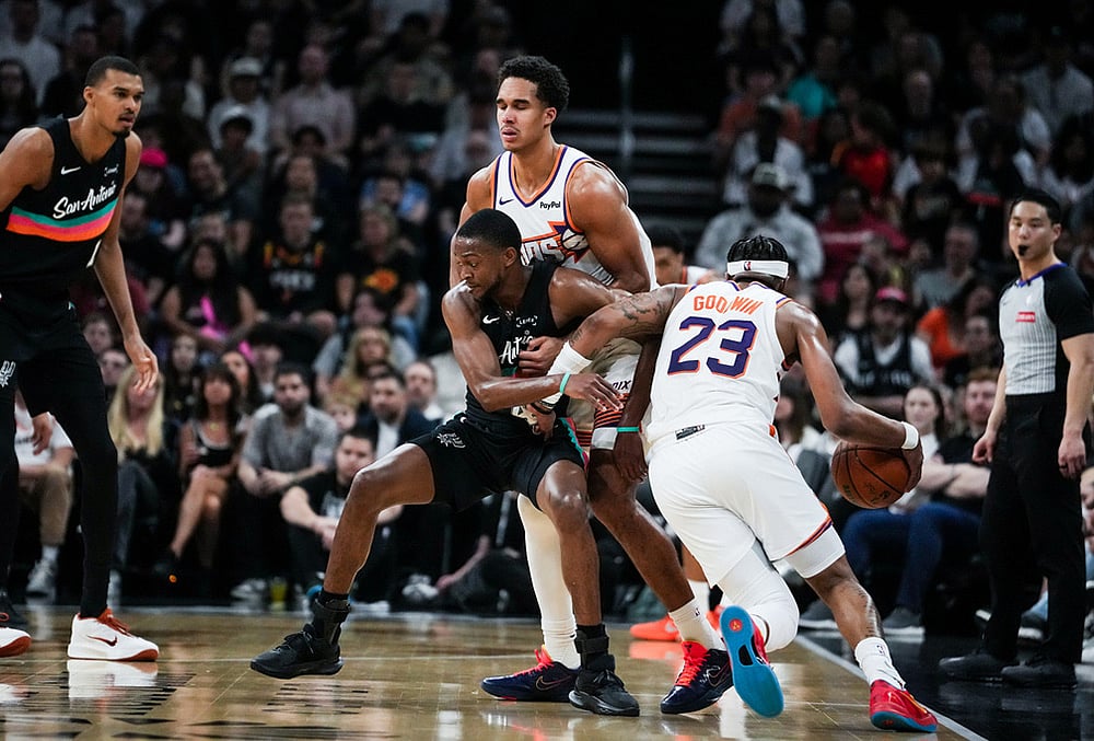 | Photo: Sara Diggins/Austin American-Statesman via AP : Phoenix Suns guard Jordan Goodwin (23) drives past defense from San Antonio Spurs forward Harrison Barnes (40) as Barnes is held up by Phoenix Suns forward Ryan Dunn (0) in the second quarter of an NBA basketball game in Austin, Texas.