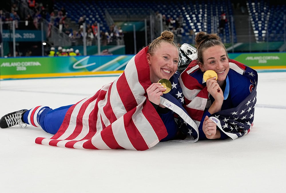 | Photo: AP/Hassan Ammar : United States Grace Zumwinkle, left, and Taylor Heise celebrate after victory ceremony for womens ice hockey at the 2026 Winter Olympics, in Milan, Italy.
