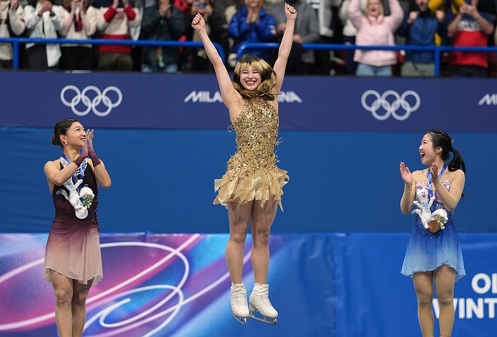 | Photo: AP/Stephanie Scarbrough : From left to right, silver medalist Kaori Sakamoto of Japan, gold medalist Alysa Liu of the United States, and bronze medalist Ami Nakai of Japan, jump on the podium to receive their medals after competing in the womens free skate program in figure skating at the 2026 Winter Olympics, in Milan, Italy.
