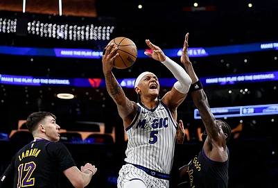 | Photo: AP/Caroline Brehman : Orlando Magic forward Paolo Banchero (5) drives to the basket with the ball while being guarded by Los Angeles Lakers forward Jake LaRavia (12) and Los Angeles Lakers center Deandre Ayton (5) during the first half of an NBA basketball game in Los Angeles.