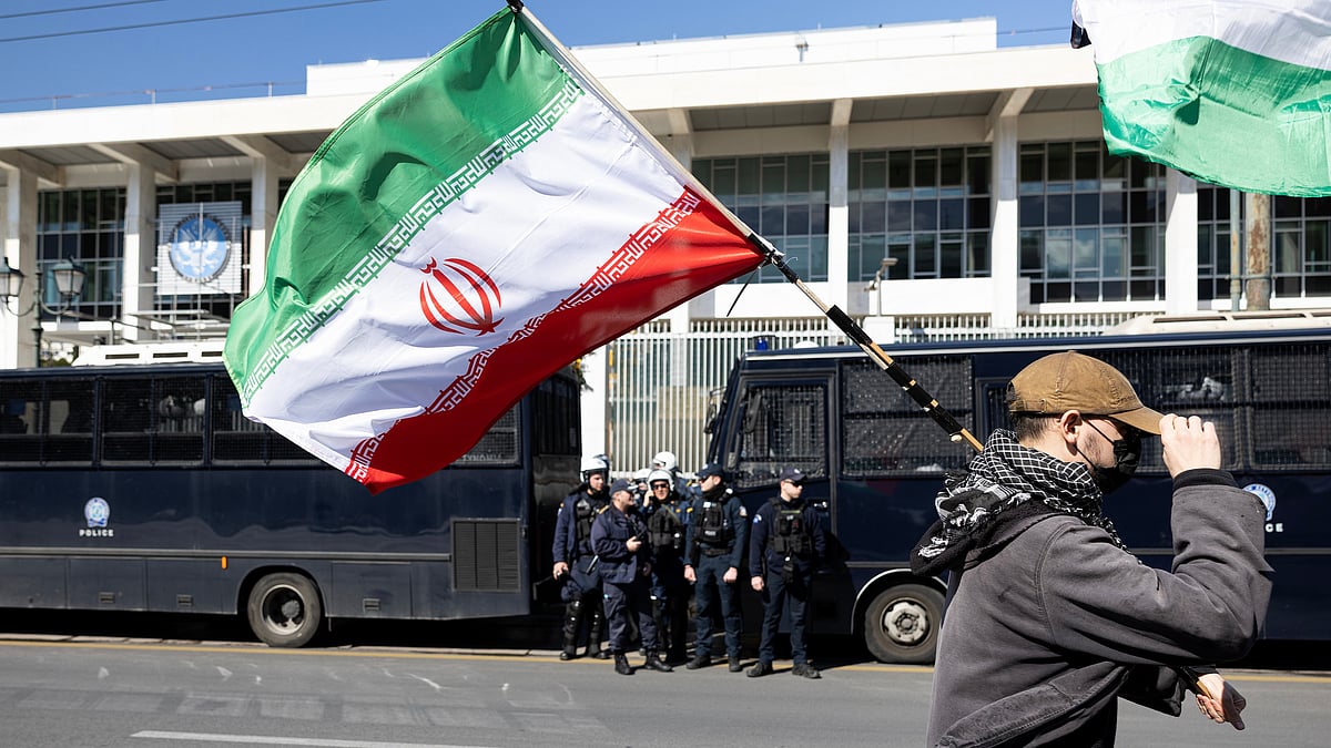 | Photo: AP/Yorgos Karahalis : A protester waves an Iranian flag during a rally against U.S. and Israeli strikes on Iran, outside the U.S. embassy in Athens, Greece, Sunday, Mar. 1, 2026.