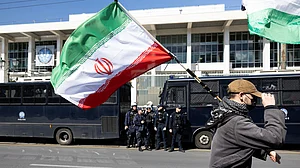 | Photo: AP/Yorgos Karahalis : A protester waves an Iranian flag during a rally against U.S. and Israeli strikes on Iran, outside the U.S. embassy in Athens, Greece, Sunday, Mar. 1, 2026.