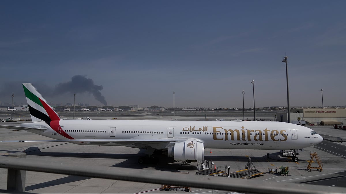Altaf Qadri : A plume of smoke caused by an Iranian strike is seen in the background an an Emirates plane is parked at the Dubai International Airport after its closure in Dubai, United Arab Emirates, Sunday, March 1, 2026.
