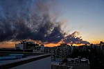 AP News : The sun sets behind a plume of smoke rising after a U.S.–Israeli military strike in Tehran, Iran, Tuesday, March 3, 2026.