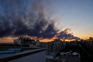 AP News : The sun sets behind a plume of smoke rising after a U.S.–Israeli military strike in Tehran, Iran, Tuesday, March 3, 2026.