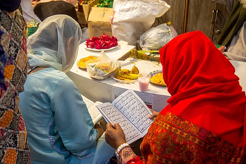 Noor Nisha : Two women read while waiting to break their fast at Nizamuddin Dargah during Ramadan.