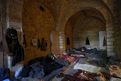 | Photo: AP/Hussein Malla : A displaced migrant man who was among others who fled Israeli strikes in southern and eastern Lebanon and Beiruts southern suburbs checks his mobile phone as he sits on a mattress at Saint Joseph Church, which has been turned into a shelter for displaced migrants, mostly from African nations, in Beirut, Wednesday, March 11, 2026.