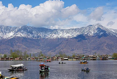 | Photo: PTI : Shikaras ferry tourists on the Dal Lake with snow-clad mountains in the backdrop, in Srinagar.