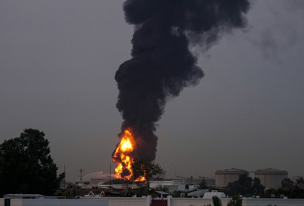 | Photo: AP : Fire and plumes of smoke rises after a drone struck a fuel tank forcing the temporary suspension of flights. near Dubai International Airport, in United Arab Emirates, early Monday, March 16, 2026. 
