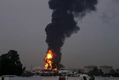 | Photo: AP : Fire and plumes of smoke rises after a drone struck a fuel tank forcing the temporary suspension of flights. near Dubai International Airport, in United Arab Emirates, early Monday, March 16, 2026.