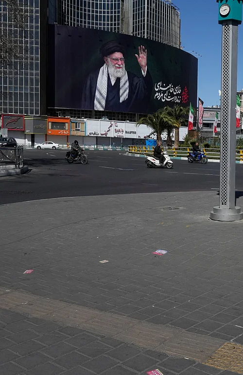 AP : A woman crosses almost deserted square with a billboard at rear showing a portrait of the late Iranian Supreme Leader Ayatollah Ali Khamenei, who was killed in the U.S.–Israeli military campaign, in Tehran, Iran, Tuesday, March 3, 2026. (AP Photo/Vahid Salemi)