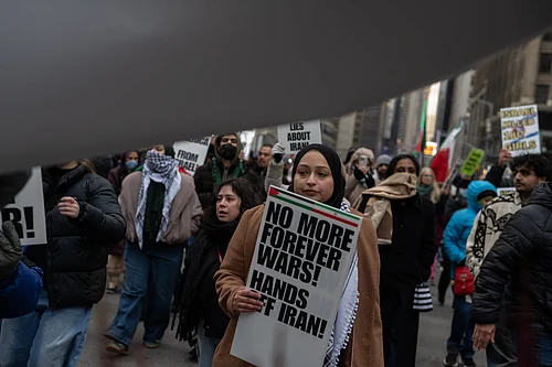 Source: IMAGO / ZUMA Press Wire : March 13, 2026, New York, New York, USA: A woman carries a sign that reads, No More Forever Wars! Hands Off Iran! at an Al Quds Day rally in Times Square marching to Herald Square to mark the last day of Ramadan and to protest the US-Israel war on Iran.