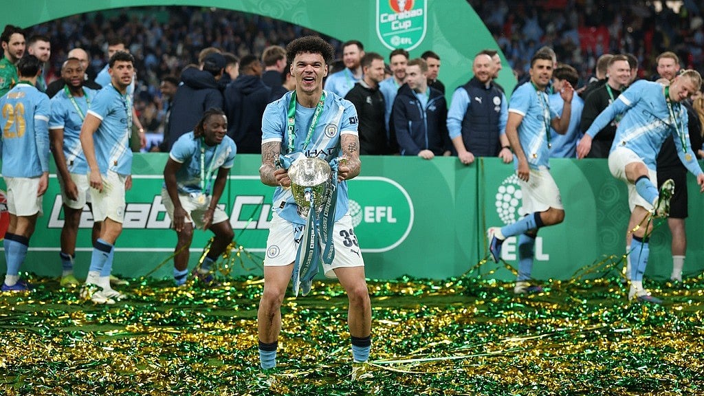 AP Photo  : Manchester City's Nico O'Reilly celebrates with the trophy after winning the English League Cup final soccer match between Arsenal and Manchester City in London, Sunday, March 22, 2026.
