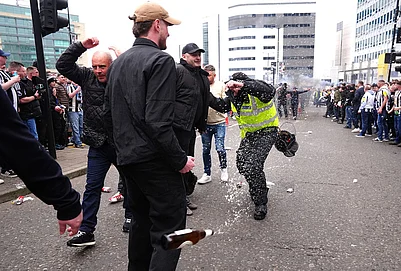 | Photo: Owen Humphreys/PA via AP : A police officer reacts as a bottle is thrown during clashes between Sunderland and Newcastle United fans before the Premier League match between Newcastle and Sunderland outside St James Park, Newcastle upon Tyne, England.