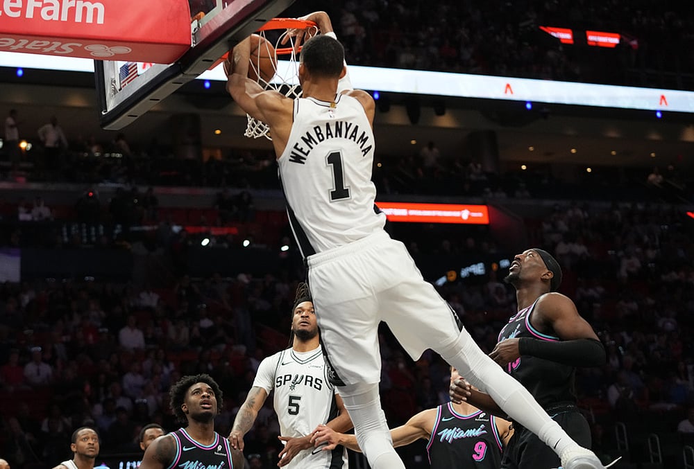| Photo: AP/Lynne Sladky : San Antonio Spurs forward Victor Wembanyama (1) dunks over Miami Heat center Bam Adebayo, right, during the first half of an NBA basketball game in Miami. 