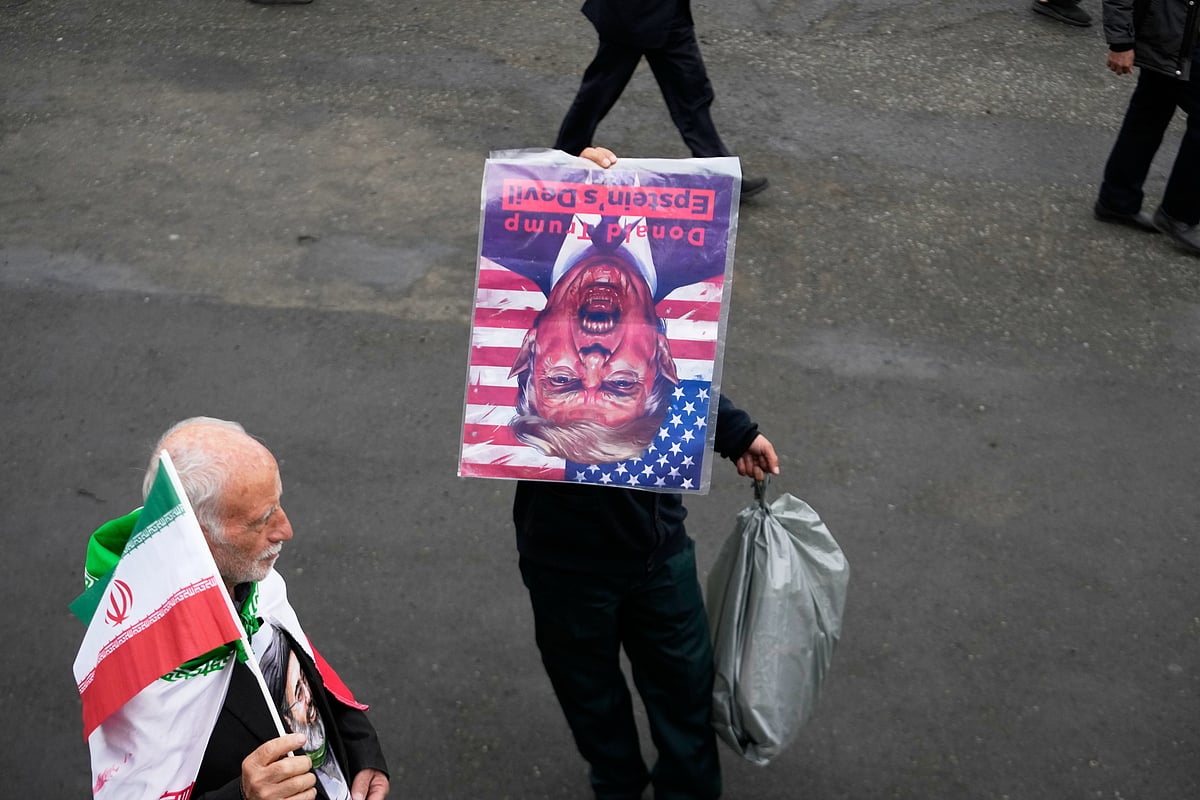 AP Photo/Vahid Salemi : A man holds a picture of U.S. President Donald Trump upside down after Friday prayers at the Imam Khomeini Grand Mosque in Tehran, Iran, Friday, March 20, 2026