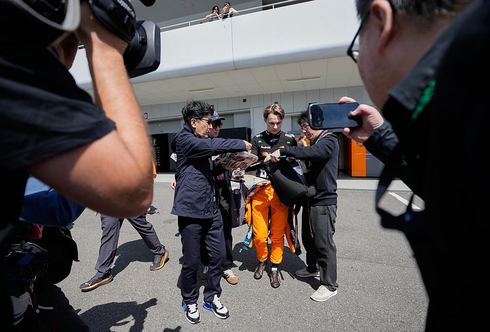 | Photo: AP/Eugene Hoshiko : McLaren driver Oscar Piastri of Australia gives autograph to fans after the first practice session of the Japanese Formula One Grand Prix in Suzuka, Japan.