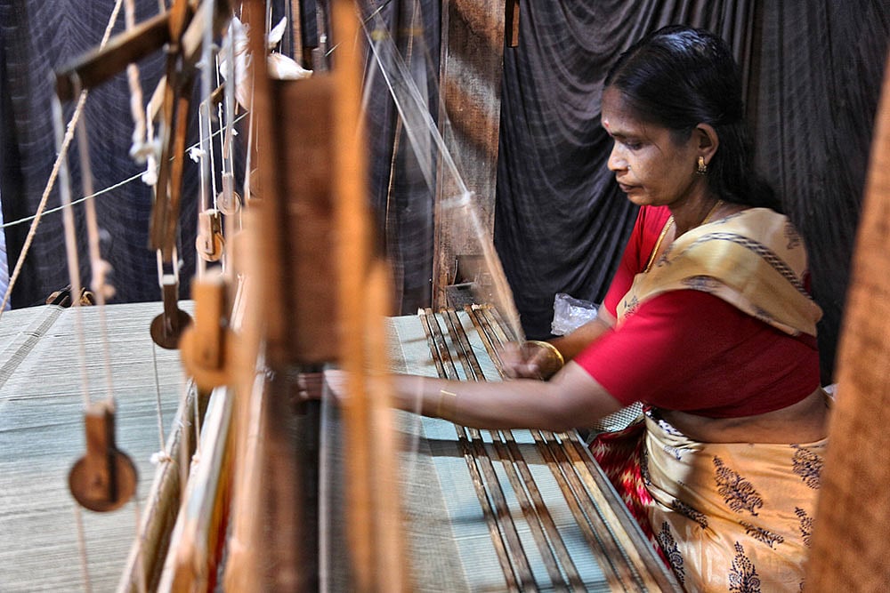 | Photo: IMAGO/NurPhoto : Integrated Tribal Development Project At The Ente Keralam Expo Woman demonstrates weaving cloth on a large loom as part of the Integrated Tribal Development Project (ITDP) during the Ente Keralam Expo in Thiruvananthapuram (Trivandrum), Kerala, India