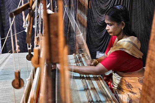 | Photo: IMAGO/NurPhoto : Integrated Tribal Development Project At The Ente Keralam Expo Woman demonstrates weaving cloth on a large loom as part of the Integrated Tribal Development Project (ITDP) during the Ente Keralam Expo in Thiruvananthapuram (Trivandrum), Kerala, India
