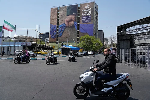 AP : Motorbikes drive past a billboard that shows a graphic depicting a military personnels hand holding the Strait of Hormuz in his fist with signs which read in Farsi: In Irans hands forever, Trump couldnt do a damn thing, The control of Strait of Hormuz will be Irans forever, in Vanak Square in northern Tehran, Iran, Thursday, April 16, 2026.