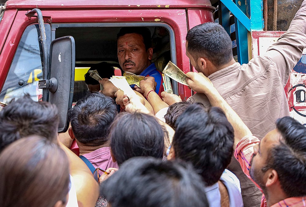 | Photo: PTI : People rush to pay and collect LPG cylinders from a delivery truck carrying cylinders amid the ongoing supply crisis, at the McLeodganj Chowk, in Dharamshala, Himachal Pradesh.